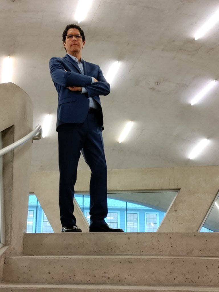 Harvard Music Professor Alejandro Madrid poses at the top of a stone staircasef